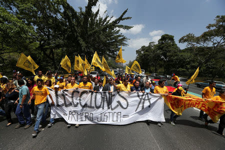 Opposition supporters hold a banner that reads, "Elections now, first justice" as they block a highway during a protest against Venezuela's President Nicolas Maduro's government in Caracas, Venezuela April 3, 2017. REUTERS/Carlos Garcia Rawlins