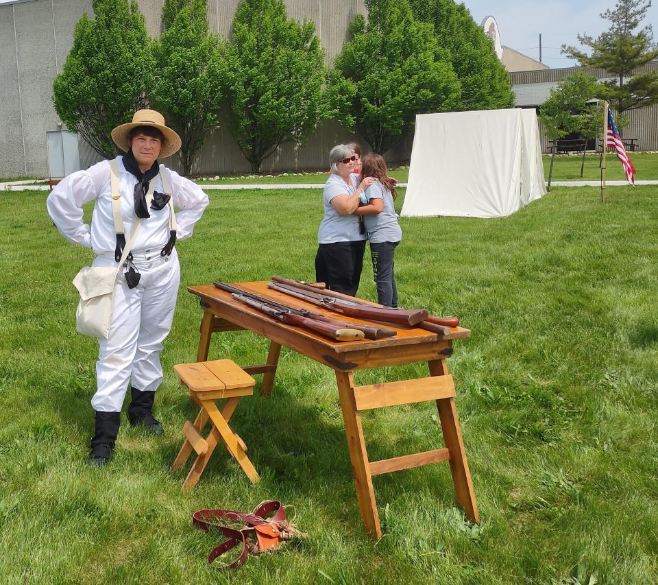 Anne Wright stands next to a table of muskets at the River Raisin National Battlefield Park.