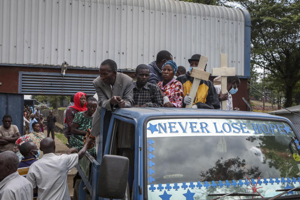 Relatives ride in the back of a truck with the coffins of villagers who were killed by suspected rebels as they retreated from Saturday's attack on the Lhubiriha Secondary School, outside the mortuary of the hospital in Bwera, Uganda Sunday, June 18, 2023. Ugandan authorities have recovered the bodies of 41 people including 38 students who were burned, shot or hacked to death after suspected rebels attacked the school in Mpondwe near the border with Congo, according to the local mayor. (AP Photo/Hajarah Nalwadda)