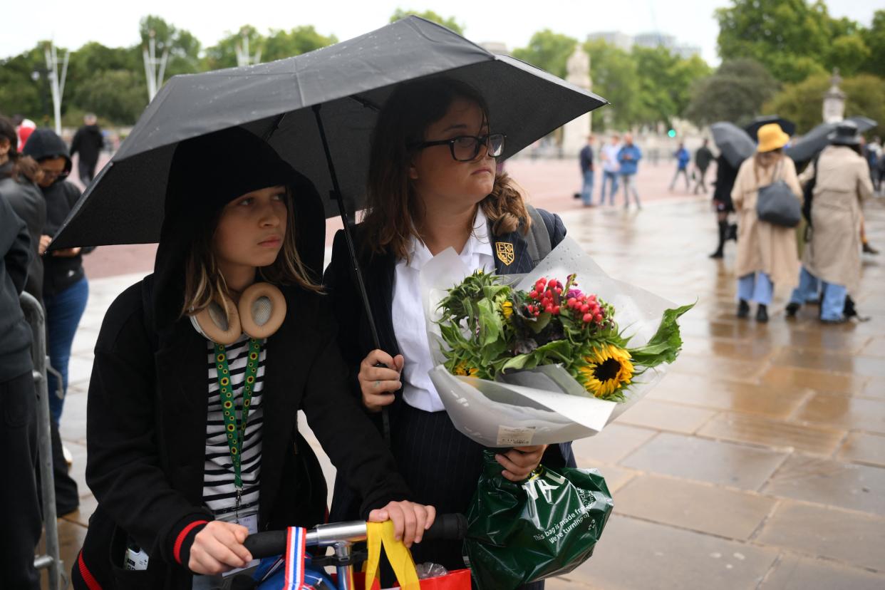 Well-wishers bring flowers as the rain falls outside Buckingham Palace, central London, on Sept. 8, 2022. 