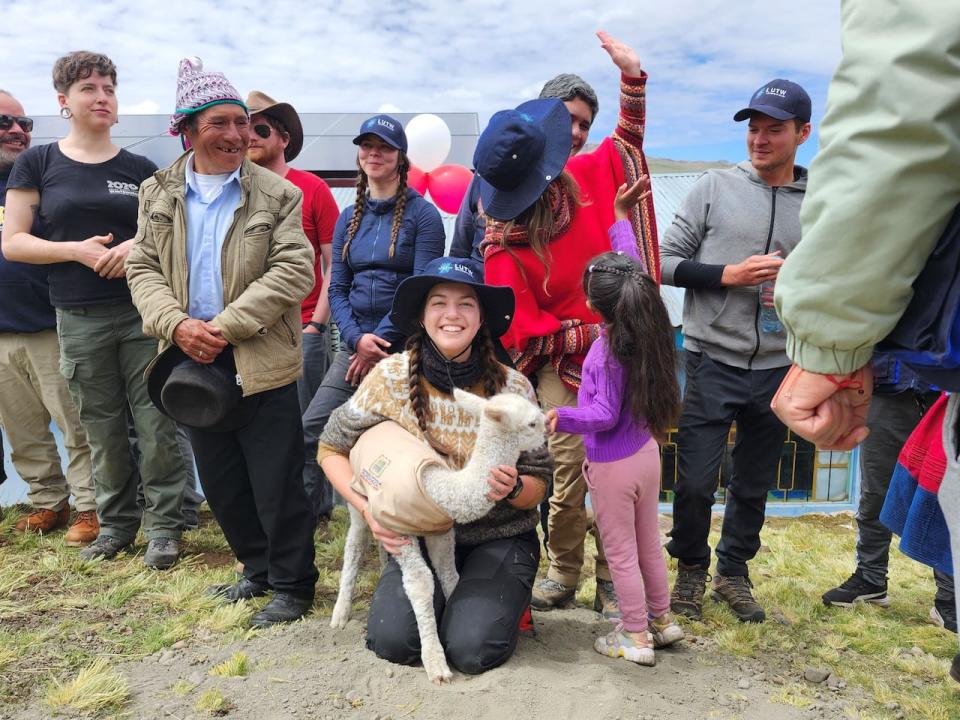 Isabelle Thériault and a one-week old alpaca with other students and a community leader.