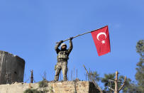 FILE -- In this Sunday, Jan. 28, 2018 file photo, a soldier waves a Turkish flag as Turkish troops secure Bursayah hill, which separates the Kurdish-held enclave of Afrin from the Turkey-controlled town of Azaz, Syria. The planned U.S. troop withdrawal opens a void in the north and east of Syria, and the conflicts and rivalries among all the powers in the Middle East are converging to fill it. (AP Photo, File)