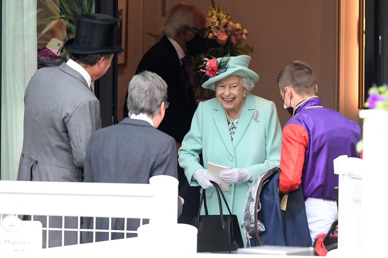 Britain's Queen Elizabeth II (2R) smiles as she meets a jockey on the fifth day of the Royal Ascot horse racing meet, in Ascot, west of London on June 19, 2021. - Royal Ascot reopened its doors to 12,000 racing fans a day but the coronavirus will still take a significant financial toll on the event. 