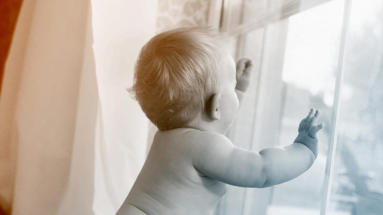 naked baby looking out window