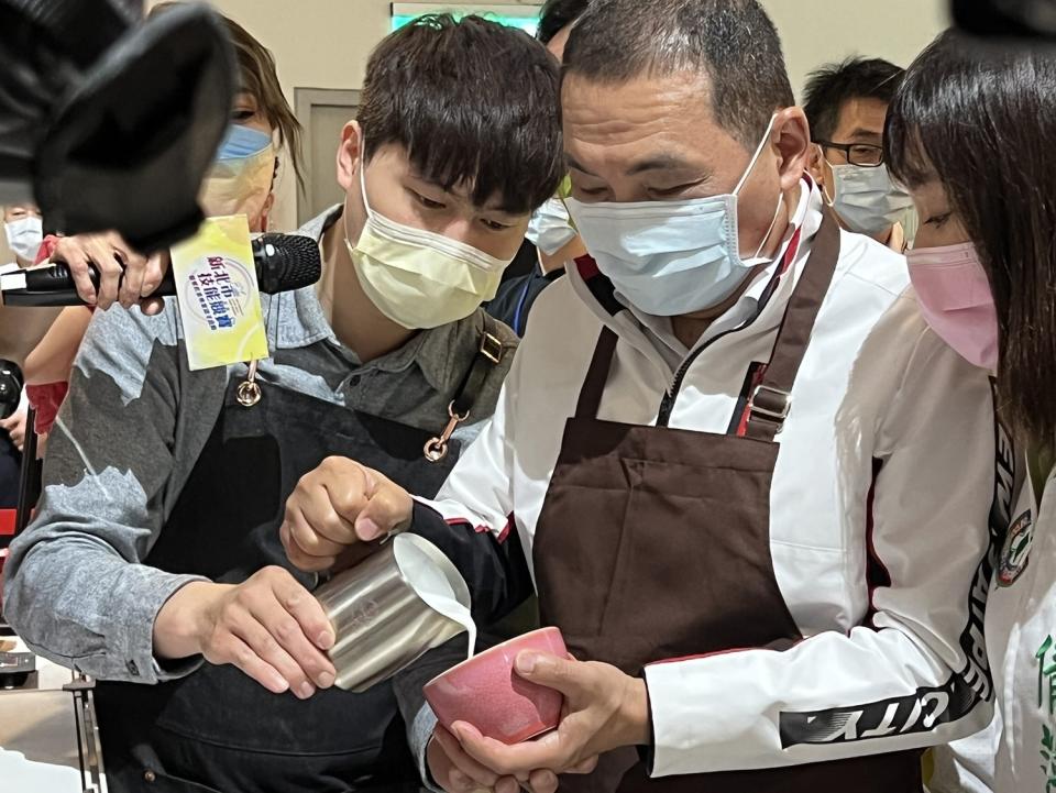 侯友宜在拉花冠軍林紹興的現場教學後，準備PK餐飲業青年。   圖：新北市職訓中心提供