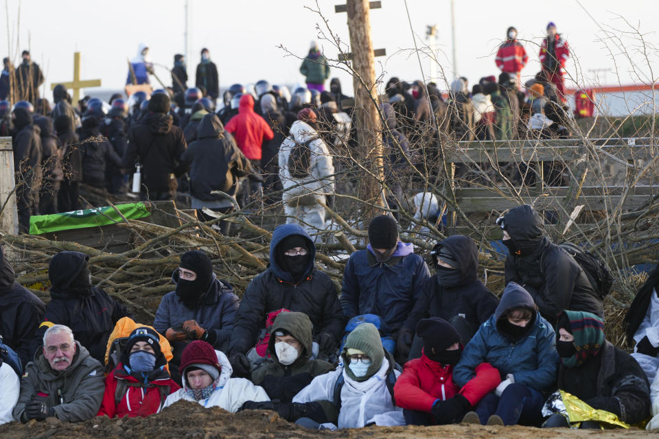 Climate activist sits on the ground at the village Luetzerath near Erkelenz, Germany, Tuesday, Jan. 10, 2023. The village of Luetzerath is occupied by climate activists fighting against the demolishing of the village to expand the Garzweiler lignite coal mine near the Dutch border. (AP Photo/Michael Probst)