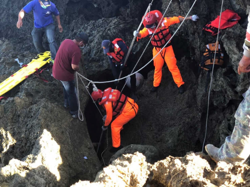 搜救人員在岸際縫隙中以繩索吊掛將吳男遺體搬運上岸。（圖／讀者提供）