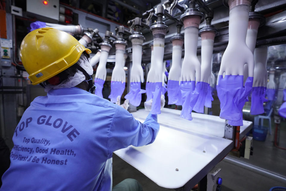 In this Wednesday, Aug. 26, 2020, file photo, a worker inspects disposable gloves at the Top Glove factory in Shah Alam on the outskirts of Kuala Lumpur, Malaysia. Malaysia's Top Glove Corp., the world's largest rubber glove maker, said Tuesday it expects a delay in deliveries after it was hit by a coronavirus outbreak that affected thousands of workers. (AP Photo/Vincent Thian)