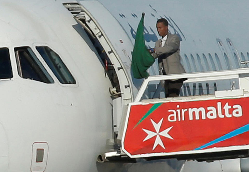 One of the hijackers of a Libyan Afriqiyah Airways Airbus A320 waves a Gaddafi-era Libyan flag at Malta Airport