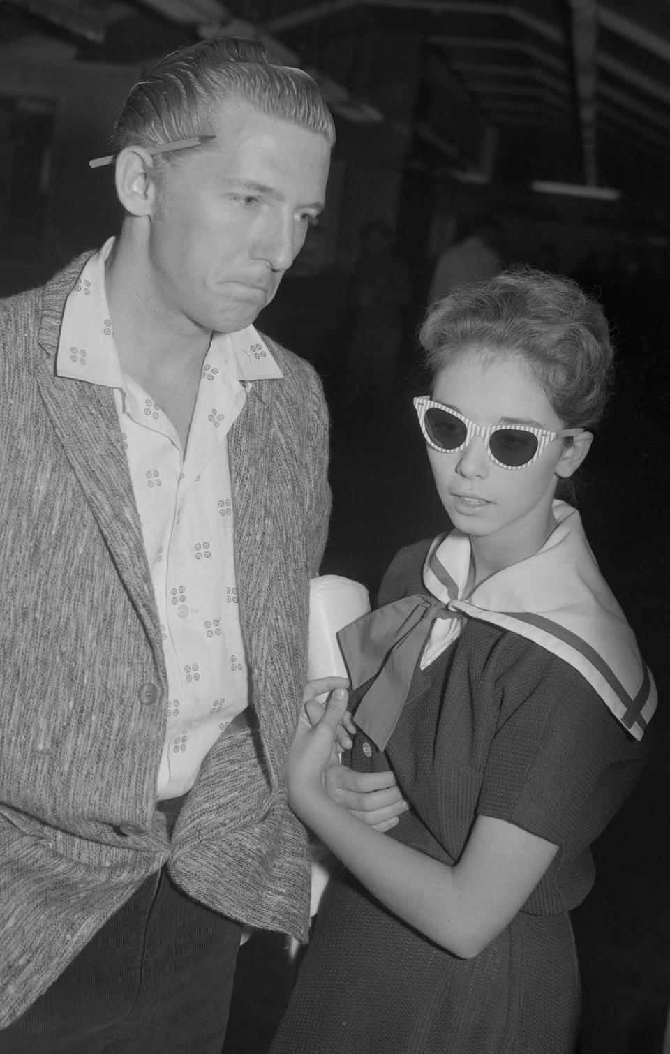 Jerry Lee Lewis and his 13-year-old bride, Myra, prepare to leave London Airport for America after the cancellation of his UK tour after he had been jeered on the stage of a London theatre. (PA)