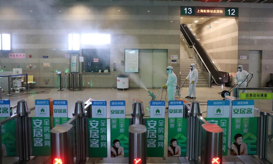 Workers in protective suits disinfect the Shanghai Hongqiao Railway Station