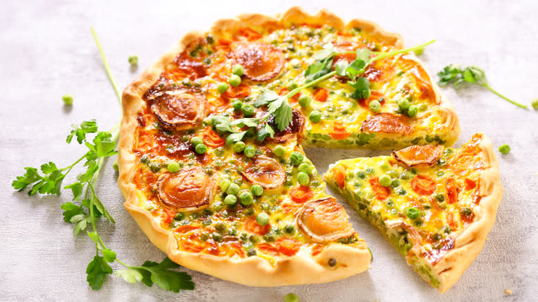 Veggie quiche with one slice cut 