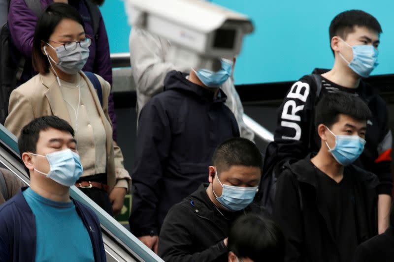 People wearing face masks are seen near a surveillance camera inside a subway station during morning rush hour in Beijing