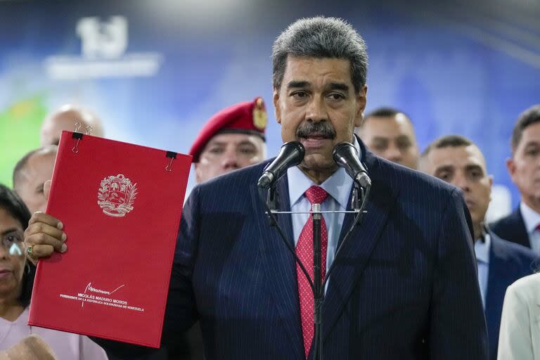 El presidente de Venezuela, Nicolás Maduro, sostiene un folleto con su nombre mientras habla con la prensa en el Tribunal Supremo en Caracas, Venezuela, miércoles 31 de julio de 2024, tres días después de su disputada reelección.