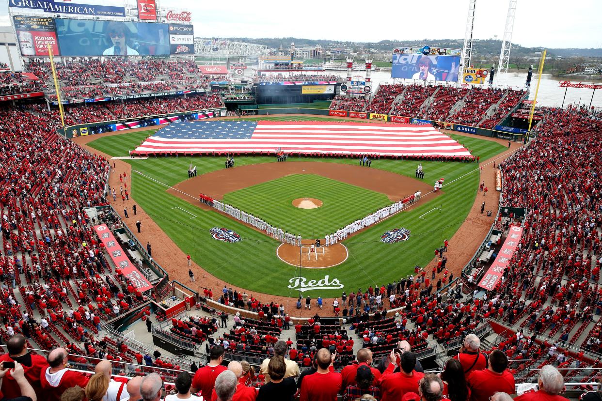 The National Anthem is sung as the American Flag is draped on the field during the Cincinnati Reds Opening Day pregame ceremony at Great American Ball Park Monday April 3, 2017. 