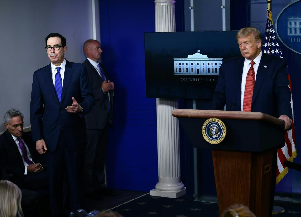 US President Donald Trump listens to Treasury Secretary Steven Mnuchin in the Brady Briefing Room of the White House in Washington, DC, on August 10, 2020. - Secret Service guards shot a person, who was apparently armed, outside the White House on Monday, President Donald Trump said just after being briefly evacuated in the middle of a press conference. The president was abruptly ushered out of the press event and black-clad secret service agents with automatic rifles rushed across the lawn north of the White House. Minutes later, Trump reappeared at the press conference, where journalists had been locked in, and announced that someone had been shot outside the White House grounds. Trump said he knew nothing about the identity or motives of the person shot, but when asked if the person had been armed, answered: "From what I understand, the answer is yes." (Photo by Brendan Smialowski / AFP) (Photo by BRENDAN SMIALOWSKI/AFP via Getty Images)