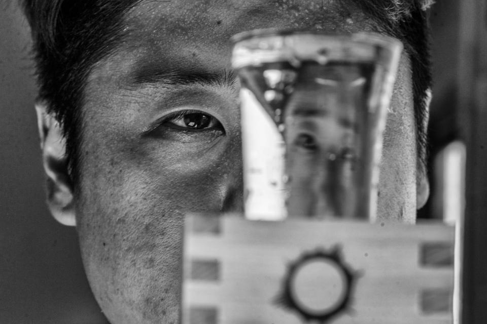 Jin peers through a glass of his craft-brewed Gravity sake.