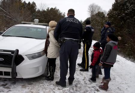 FILE PHOTO: A woman who told police that she and her family were from Sudan is taken into custody by Royal Canadian Mounted Police (RCMP) officers after arriving by taxi and walking across the U.S.-Canada border into Hemmingford, Quebec, Canada on February 12, 2017. REUTERS/Christinne Muschi/File Photo