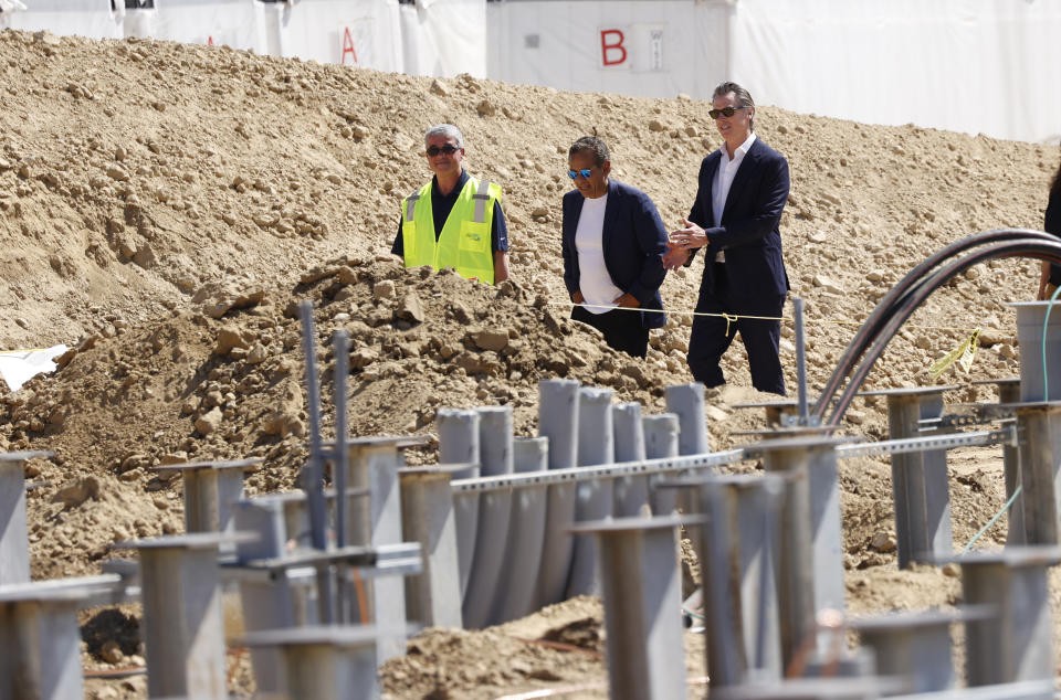 STANISLAUS COUNTY, CALIFORNIA – MAY 19: California Governor Gavin Newsom (R), former Mayor Antonio Villaraigosa (C) and Jim Shandalov, vice president at NextEra Energy Resources walk past the construction of the Battery Energy Storage Systems (BESS) for the future location of Proxima Solar Farm on May 19, 2023 in Stanislaus County, California.  The governor unveiled legislation to speed construction for a streamlined process and expedite judicial review of legal challenges that often stall projects.  The project is expected to create 300 construction jobs and generate $35 million in local revenue.  The project is expected to be operational in December, capable of powering 60,000 homes in the surrounding region and generating up to 210 megawatts of clean, renewable energy and 177 megawatts of enhanced energy storage.  (Photo by John G. Mabanglo-Pool/Getty Images)