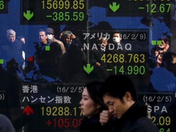 People are reflected in a display showing market indices outside a brokerage in Tokyo, Japan,  February 10, 2016. REUTERS/Thomas Peter 