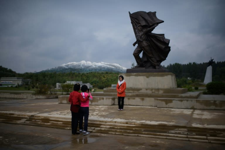 North Korean youths pose before a model of Mount Paektu at a 'Folk Park' in Pyongyang, among a number of costly "leisure" projects aimed at projecting prosperity