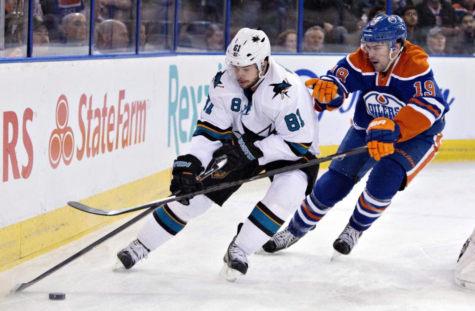 San Jose Sharks Tyler Kennedy (81) and Edmonton Oilers Justin Schultz (19) battle for the puck during the first period of an NHL hockey game in Edmonton, Alberta, on Wednesday, Jan. 29, 2014. (AP Photo/The Canadian Press, Jason Franson)