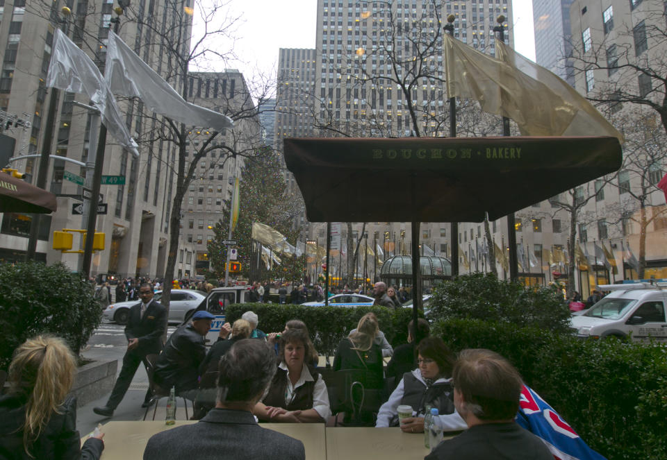 This Dec. 5, 2013 photo shows patrons of Bouchon Bakery at sidewalk tables near the Christmas tree, in New York's Rockefeller Center. Rockefeller Center is crowded at Christmastime thanks to the famous tree, the skating rink and the show at Radio City Music Hall, but visitors can choose from a variety of places to eat in the area, from ethnic food and street carts to sit-down dining. (AP Photo/Richard Drew)