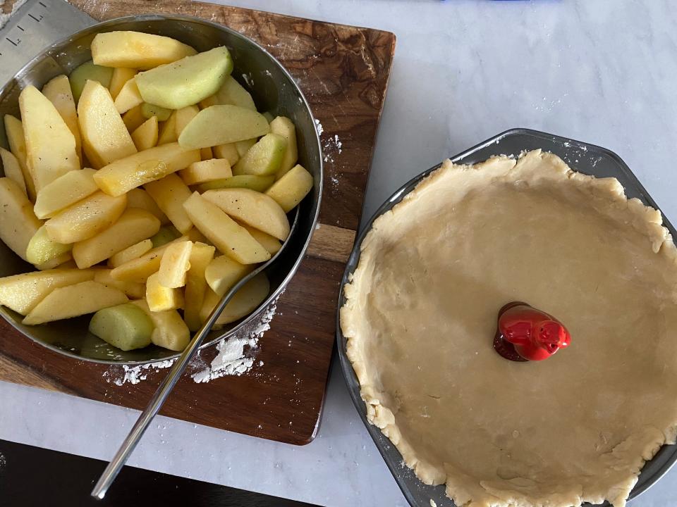 Apple slices next to an open pie crust.