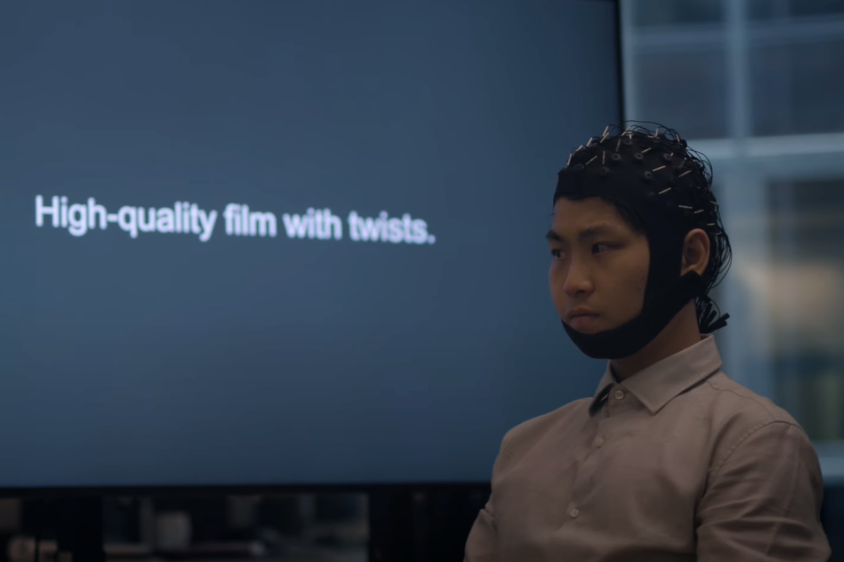 A participant of the mind-reading study wears a cap that records electrical brain activity while they silently read text (UTS)