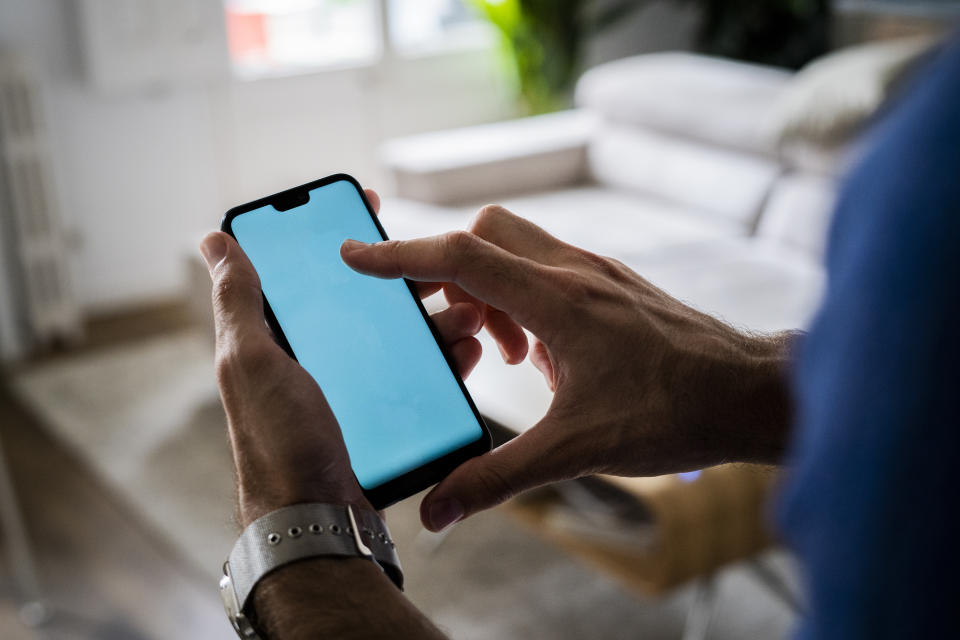 Close-up of man using cell phone at home