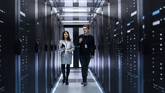 Two IT professionals walk through a data center.