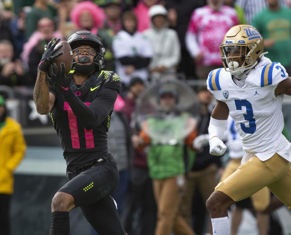 Oregon's Troy Franklin, left, pulls down a touchdown reception ahead of UCLA's Devin Kirkwood.