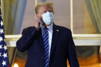 President Donald Trump removes his mask as he stands on the balcony outside of the Blue Room as returns to the White House Monday, Oct. 5, 2020, in Washington, after leaving Walter Reed National Military Medical Center, in Bethesda, Md. Trump announced he tested positive for COVID-19 on Oct. 2. (AP Photo/Alex Brandon)