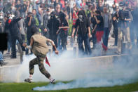 A man runs away from tear gas during clashes with French riot police during a demonstration against the government's labour reforms in Nantes, France, September 21, 2017. REUTERS/Stephane Mahe