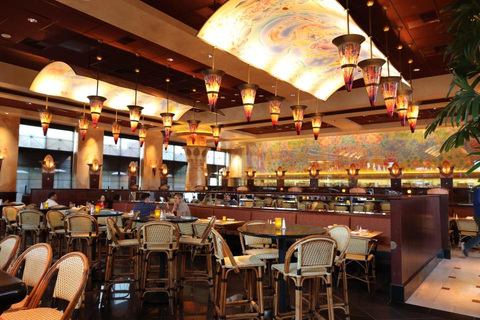 The interior of The Cheesecake Factory, which has a ceilings and lanterns hanging above several sets of chairs and tables.