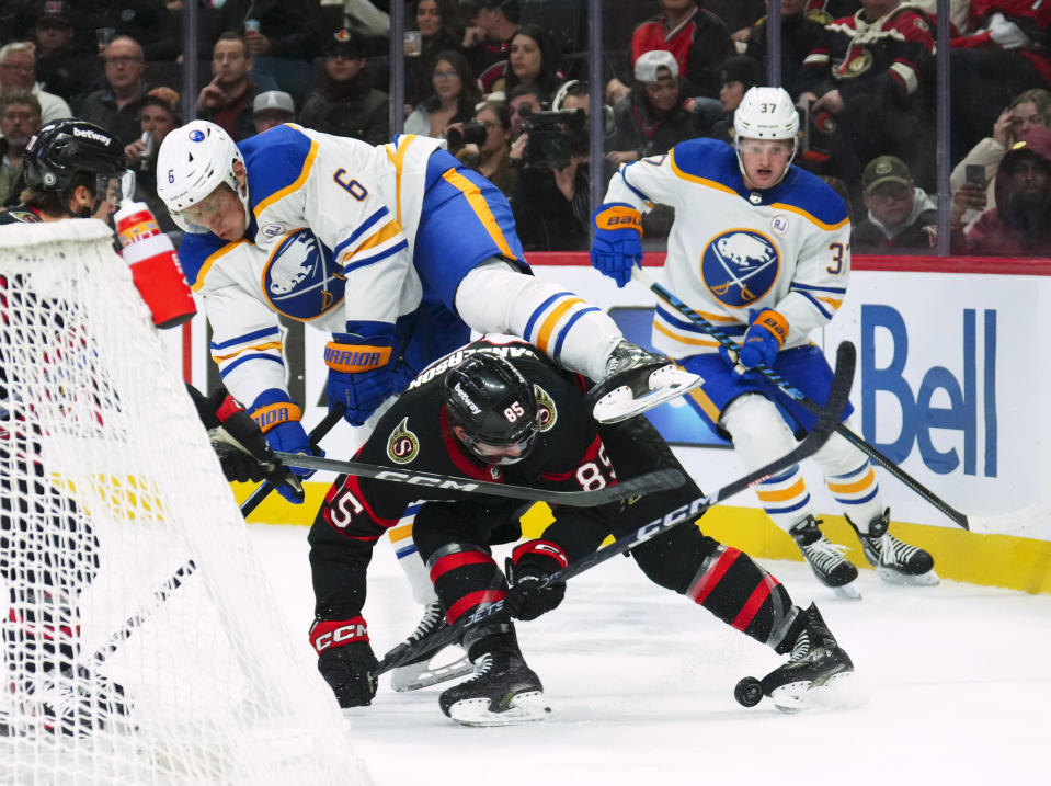 Buffalo Sabres defenceman Erik Johnson (6) gets caught up on the back of Ottawa Senators defenseman Jake Sanderson (85) during the second period of an NHL hockey game Tuesday, Oct. 24. 2023, in Ottawa, Ontario. (Sean Kilpatrick/The Canadian Press via AP)