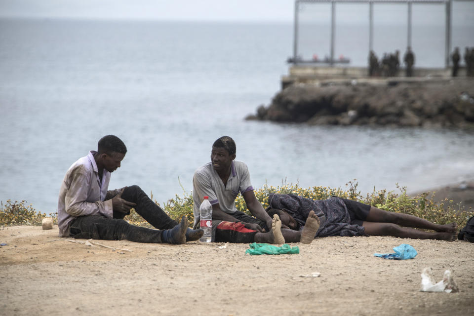 Men sit on the ground after arriving in the Spanish territory at the border of Morocco and Spain, at the Spanish enclave of Ceuta, on Tuesday, May 18, 2021. Ceuta, a Spanish city of 85,000 in northern Africa, faces a humanitarian crisis after thousands of Moroccans took advantage of relaxed border control in their country to swim or paddle in inflatable boats into European soil. Around 6,000 people had crossed by Tuesday morning since the first arrivals began in the early hours of Monday, including 1,500 who are presumed to be teenagers. (AP Photo/Javier Fergo)