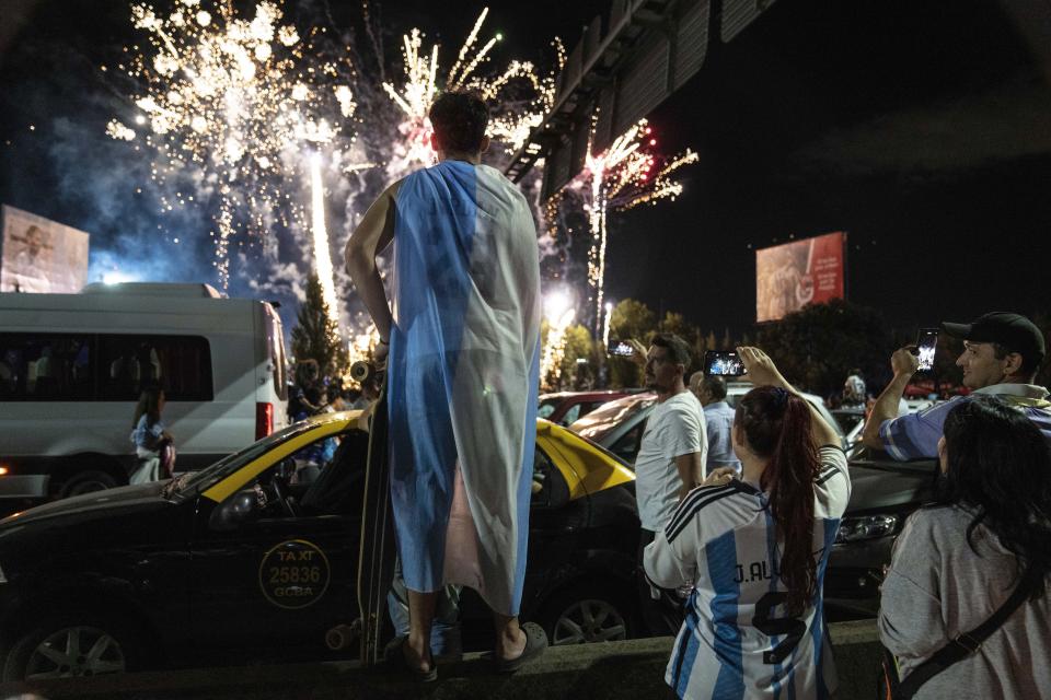 Soccer fans watch fireworks welcoming home the players from the Argentine soccer team that won the World Cup after they landed at Ezeiza airport on the outskirts of Buenos Aires, Argentina, Tuesday, Dec. 20, 2022. (AP Photo/Rodrigo Abd)
