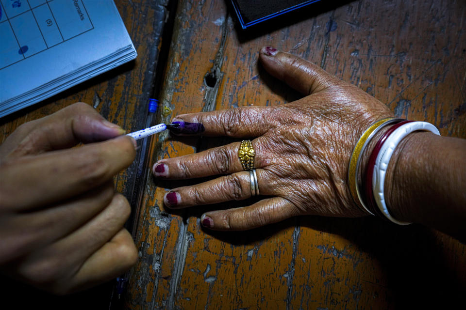 A polling official puts indelible ink mark on the index finger of an elderly woman voter at a polling station during the third phase of general election in Guwahati, Assam, India, Tuesday, May 7, 2024. (AP Photo/Anupam Nath)