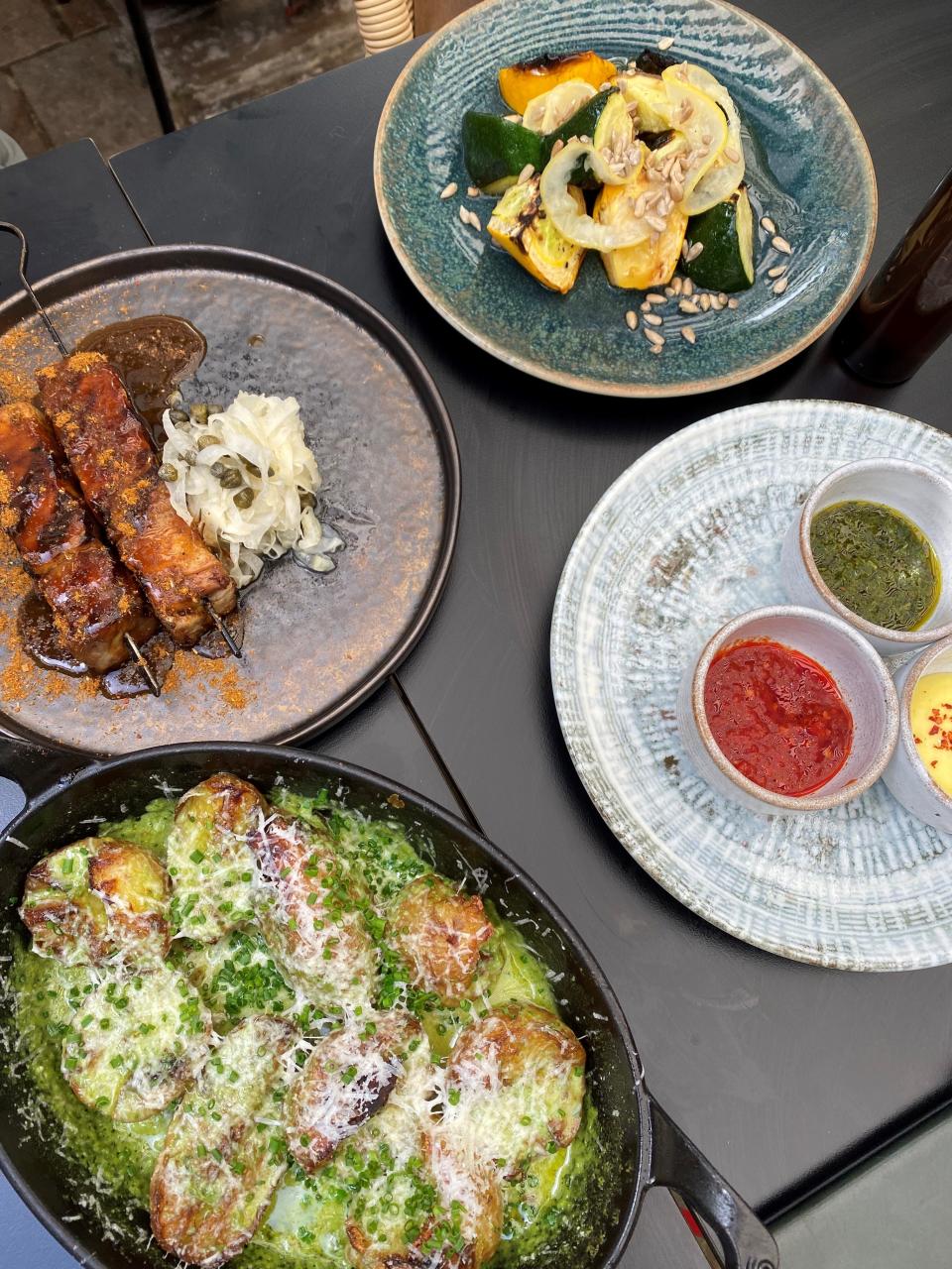 Clockwise from bottom left: herby, cheesy baked potatoes; pork belly shawarma; heritage courgettes; and dips (Molly Codyre)