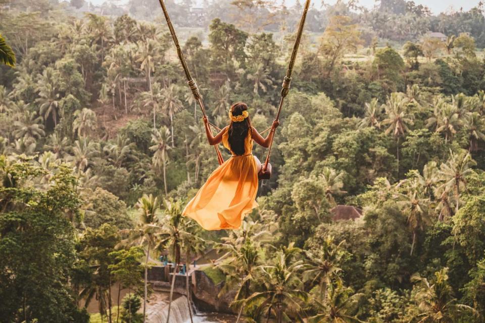 Woman with long swing and forest view in Indonesia