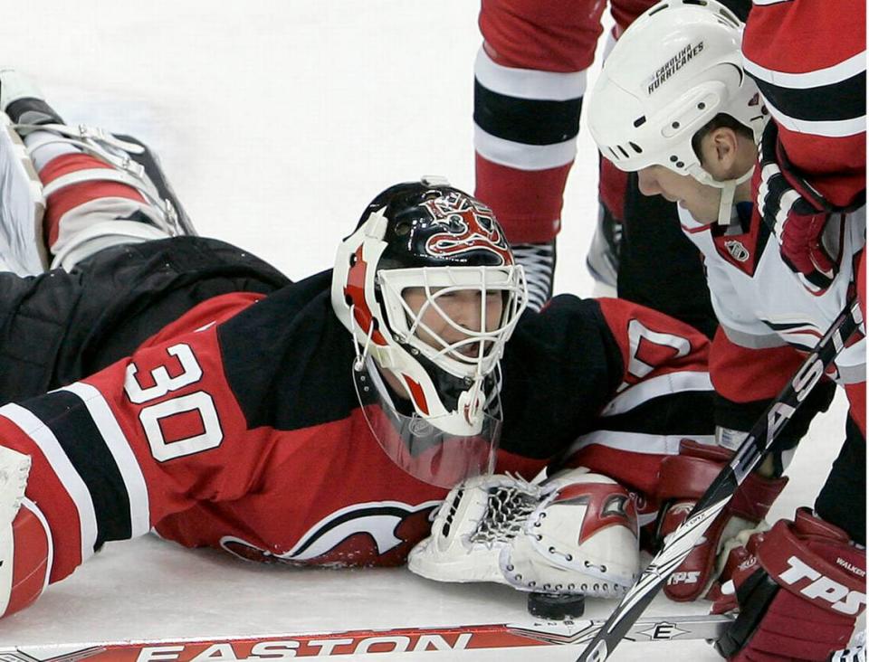 New Jersey Devils' goalie Martin Brodeur (30) covers the puck with his glove as he makes a save and looks at Carolina Hurricanes' Scott Walker, right, during the third period.