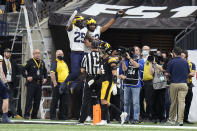 Michigan tight end Erick All celebrates with teammate Hassan Haskins (25) in front of Iowa defensive back Dane Belton (4) after catching a 5-yard touchdown pass during the second half of the Big Ten championship NCAA college football game, Saturday, Dec. 4, 2021, in Indianapolis. (AP Photo/AJ Mast)