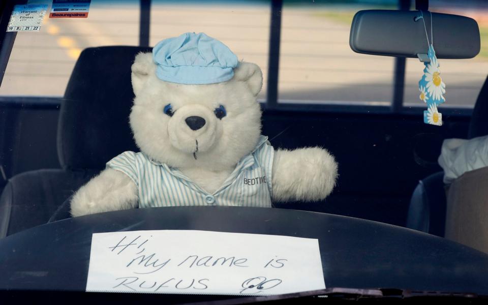 a teddy bear sits on a the wheel of a car outside a house in Christchurch - AP Photo/Mark Baker