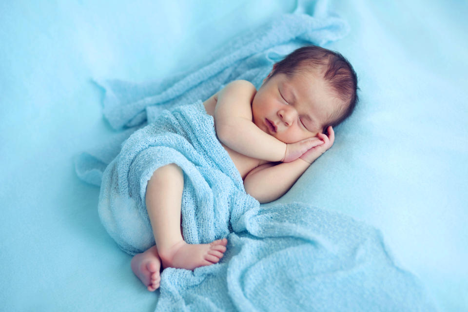Newborn baby boy in blue wrapped scarf
