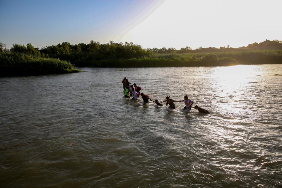 Migrants hold hands as a strong current begins to drag them as they begin to cross the Rio Grande from Piedras Negras, Mexico into Eagle Pass, Texas on July 21.