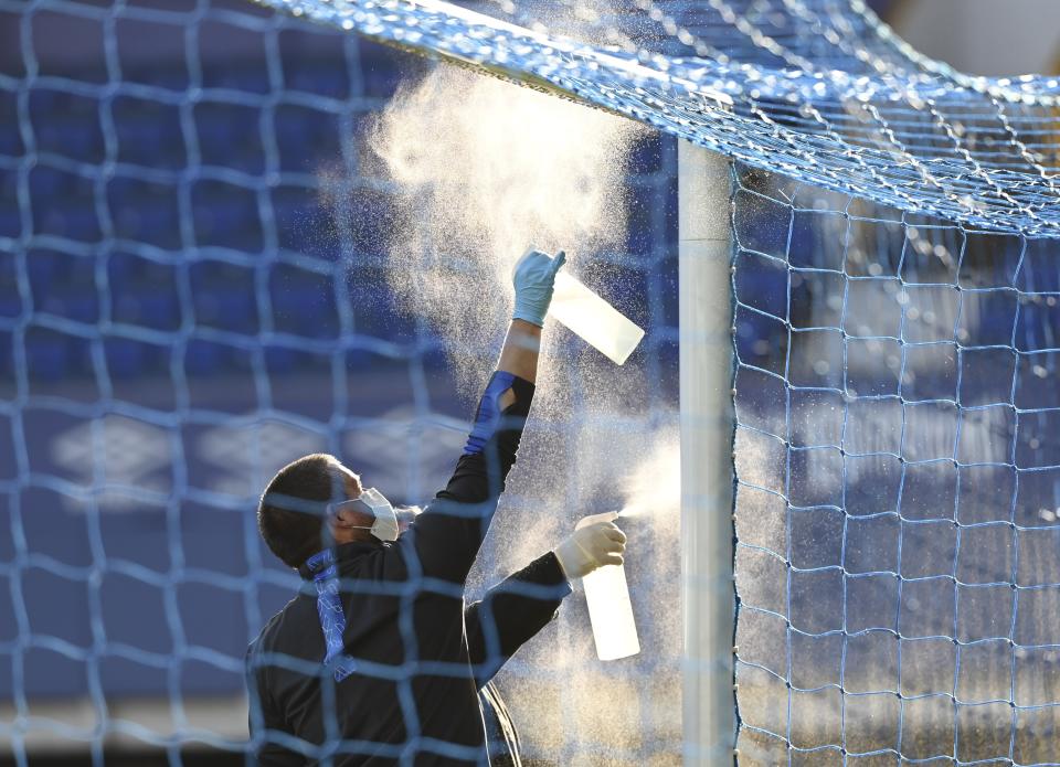 Ground staff clean the cross bar of the goals during the English Premier League soccer match between Everton and Liverpool at Goodison Park in Liverpool, England, Sunday, June 21, 2020. (AP photo/Shaun Botterill, Pool)