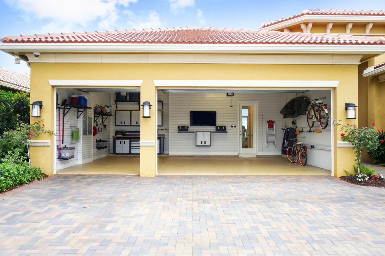 Three car garage attached to a home in a residential community.  The garage is very neat and clean.  It is well organized with shelves, bicycle racks,,a work area and storage cabinets. 