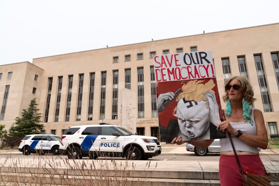 Nicky Sundt holds a banner outside the Federal District Court, Tuesday, Aug. 1, 2023 in Washington, where a grand jury has been meeting in the probe led by special counsel Jack Smith into former President Donald Trump. (AP Photo/Jose Luis Magana)
