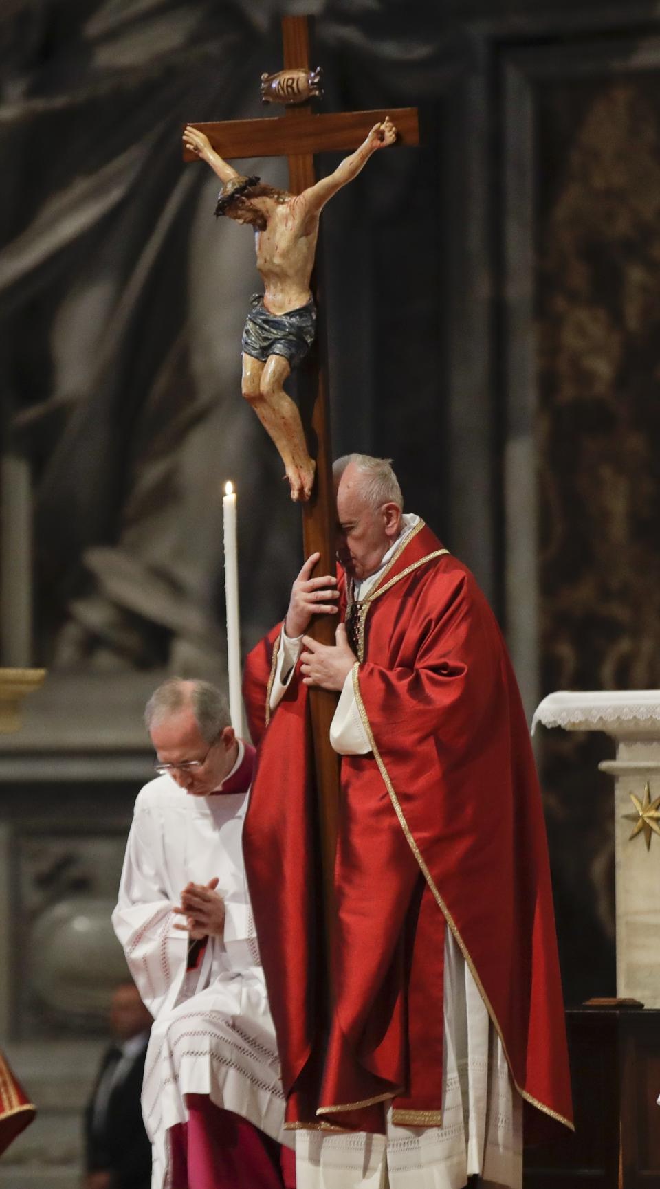 Pope Francis holds a crucifix as he celebrates Mass for the Passion of Christ, in St. Peter's Basilica, at the Vatican, Friday, April 19, 2019. Pope Francis began the Good Friday service at the Vatican with the Passion of Christ Mass and hours later will go to the ancient Colosseum in Rome for the traditional Way of the Cross procession. (AP Photo/Alessandra Tarantino)